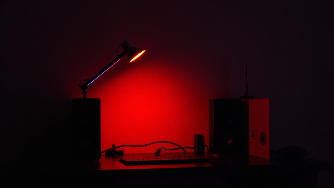 Modern RGB desk lamp glowing red on dark desk in gaming setup